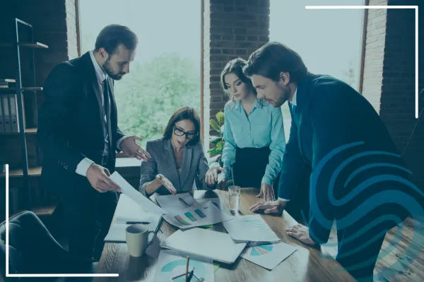 This is an image of 4 people around a table discussing business with papers on the table.  They are engaged in their conversation.  There is a Specialized Recruiting Group logo on the image.