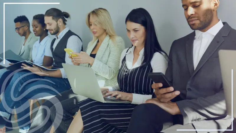 Six job seekers sitting in chairs on a wall waiting for a job interview. Each job seeker holds a phone, laptop, or report as they prepare for the interview. The Specialized Recruiting Group logo is also featured in the corner of the image.